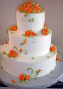 Picture of a fall wedding cake with orange flowers and green swirling.