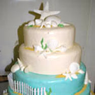 Beautiful Beach Wedding Cake with nautical colors and white fence against a blue base.