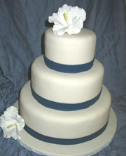 Simple and elegant three tier weding cake with blue ribbon separating each  layer wit a lovely flower topper