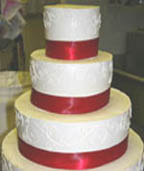 Beautiful white wedding cake with red ribbon between each layer - perfect for a Christmas theme