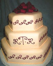 Three tier white cake with red fondant bow and couples initials